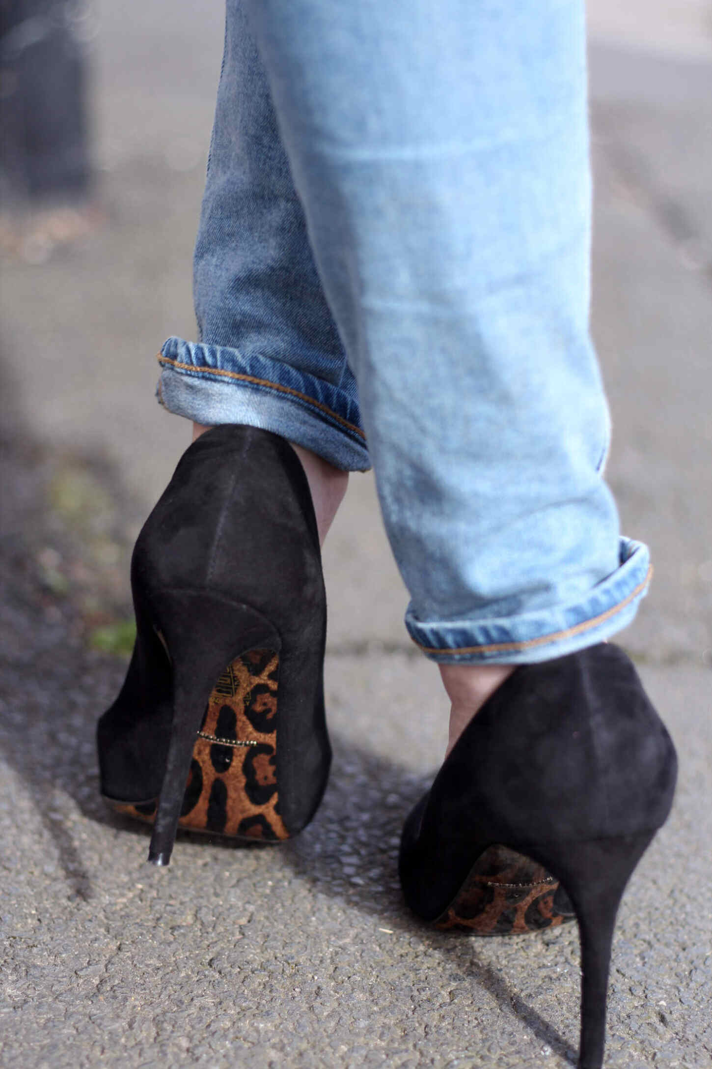 Young woman wearing a blue top, black jeans and high heels posing in front  of a gray wall with stone slabs Stock Photo - Alamy